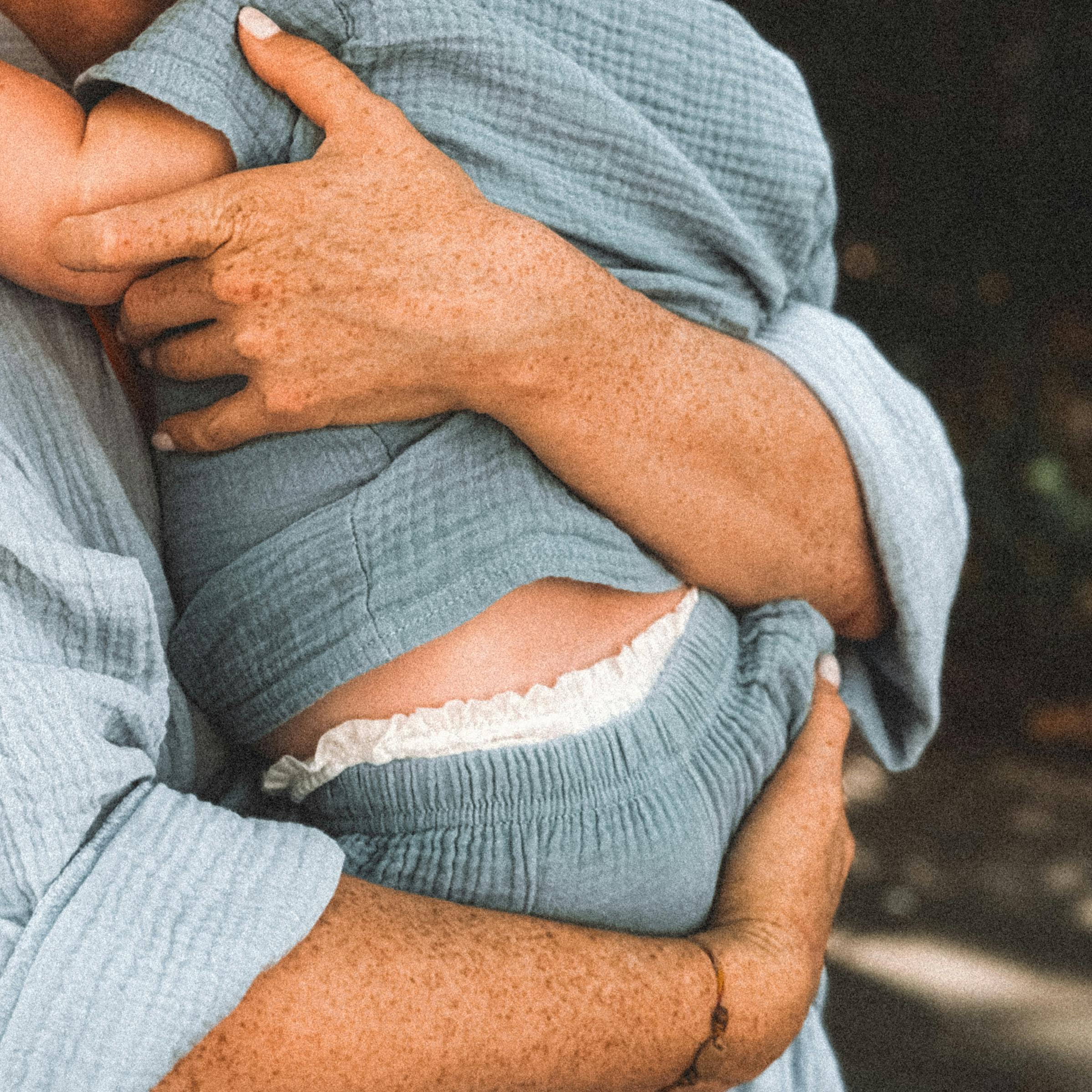 A freckled mother lovingly embraces her baby, showcasing warmth and togetherness.